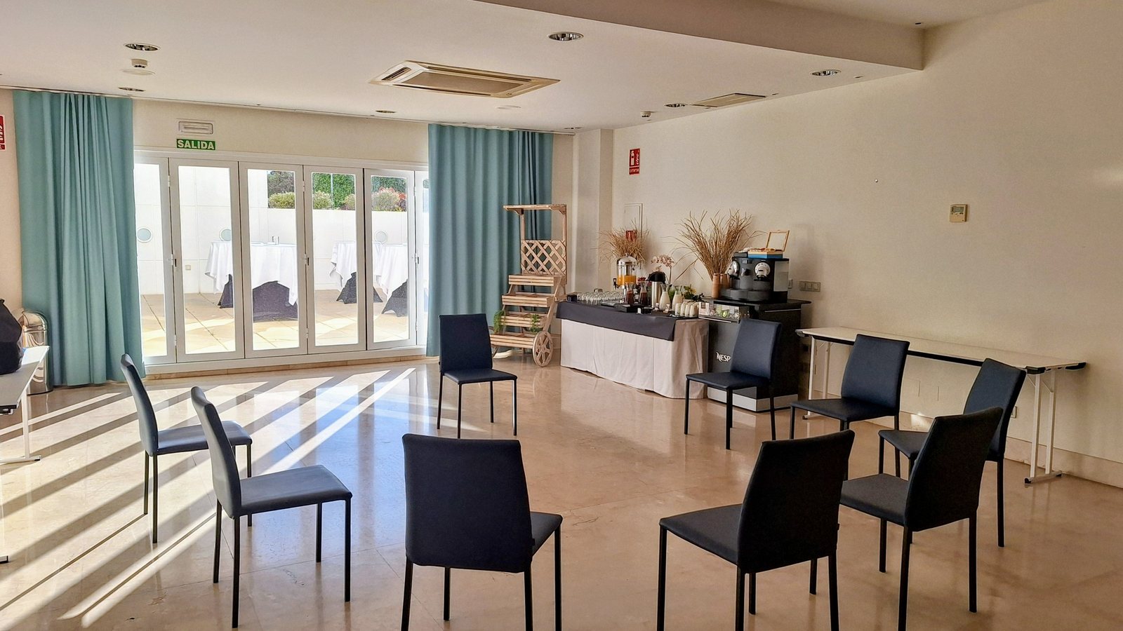 Una sala preparada antes de empezar: las sillas en círculo, la luz entrando por el ventanal y el café servido al fondo
