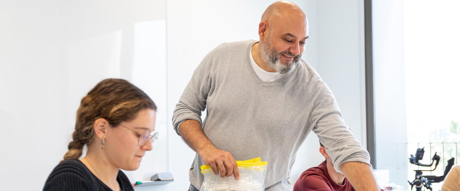 Federic de Gracia reparte las bolsas de piezas al empezar un taller, con dos participantes en la mesa